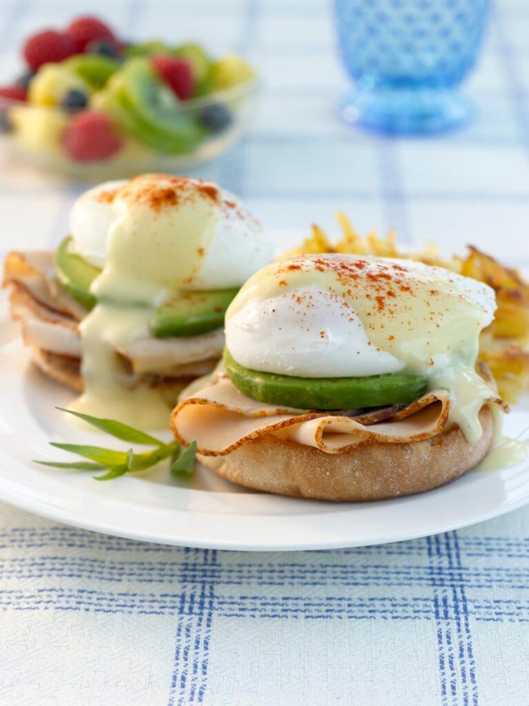 deli turkey eggs benedict on a plate with a white and blue tablecloth