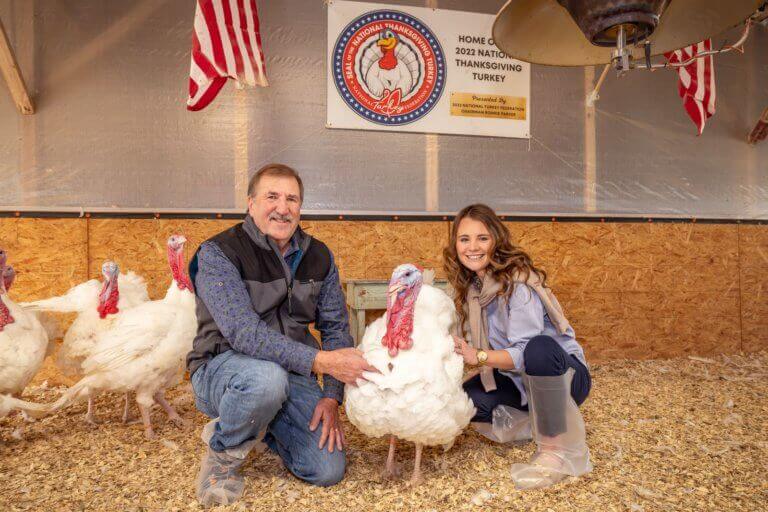 Chairman Parker sits with Chocolate, the National Thanksgiving Turkey, and Lexie Starnes inside a turkey barn.